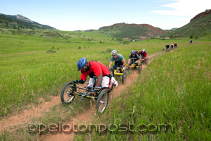 Hand cyclists crossing meadow