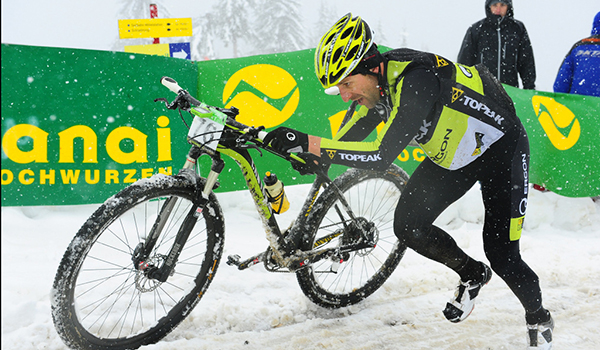 Alban Lakata pushing bike to finish